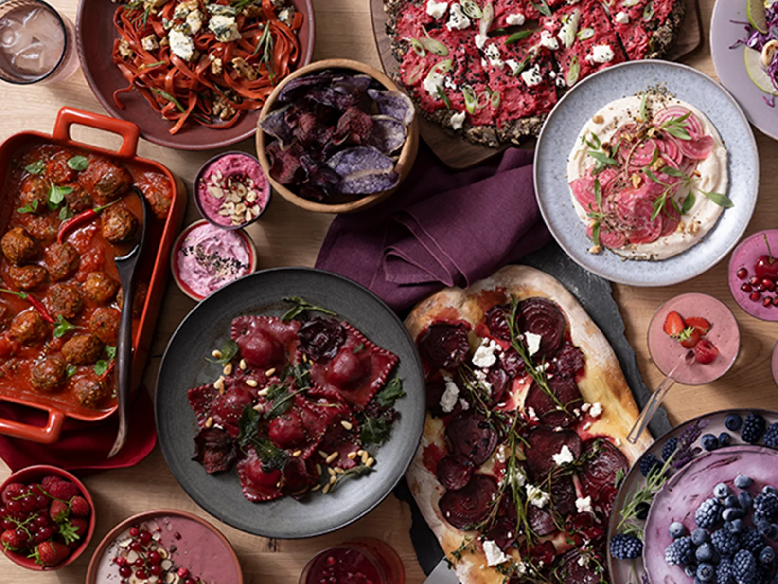 Divers plats rouges disposés sur une grande table de cuisine.