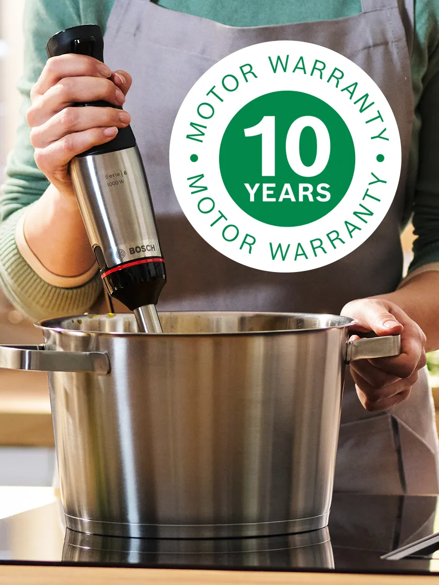 Person using Bosch hand blender in large pot on hob, with 10 Years Motor Warranty icon