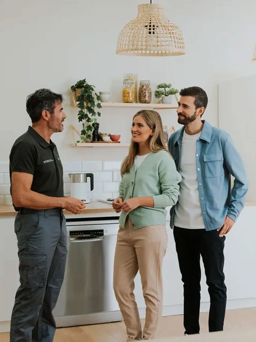 A young couple consults with a technician in a bright, modern kitchen full of Bosch appliances.