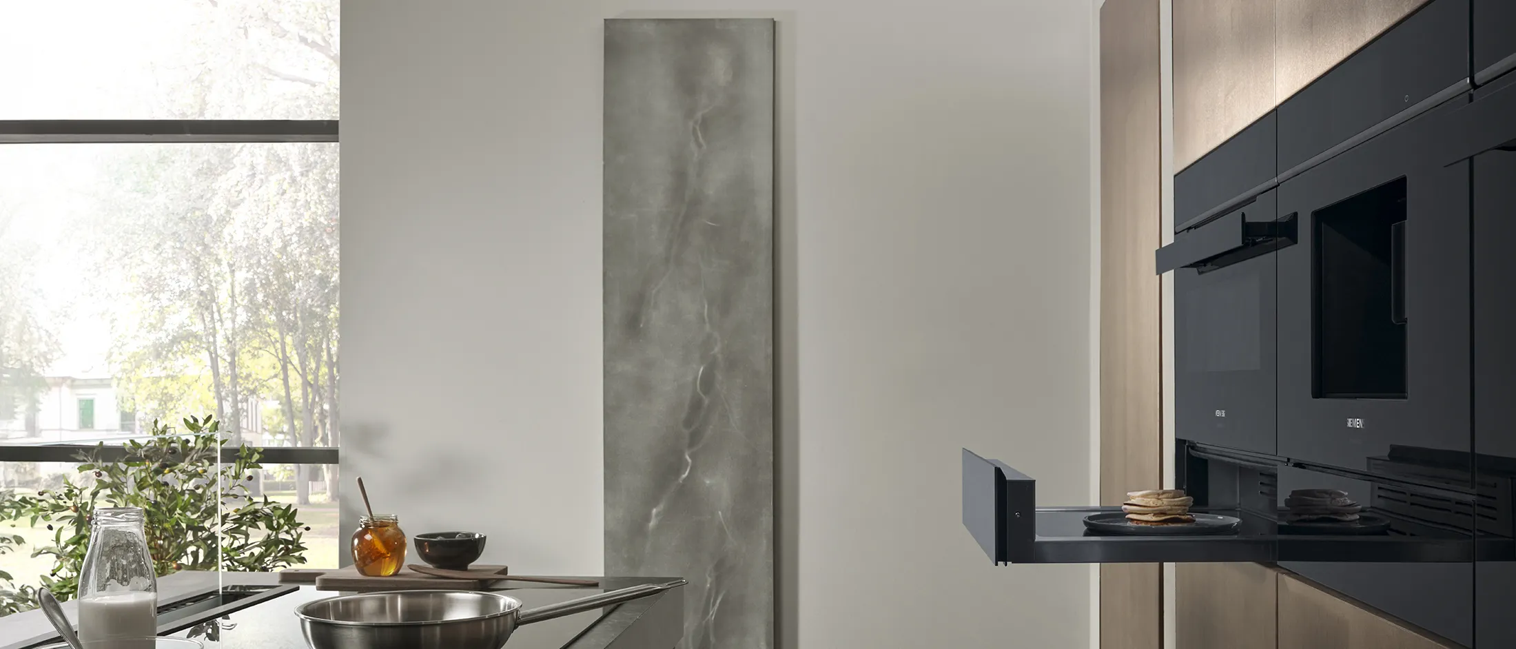 Siemens built-in warming drawer extended, seamlessly integrated into a modern kitchen with sleek appliances.