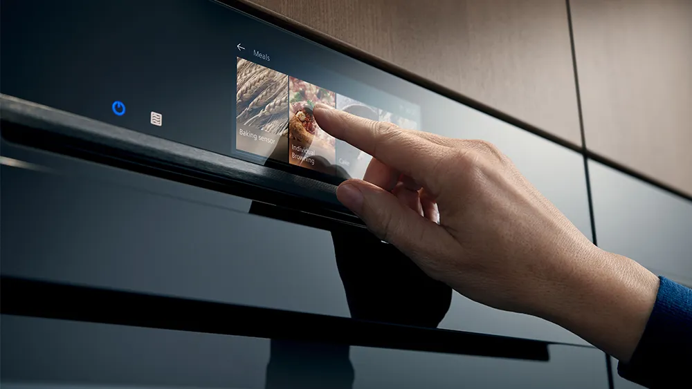 A close-up shot of a Siemens built-in oven, likely a microwave or combination oven, with its digital display and control knob illuminated
