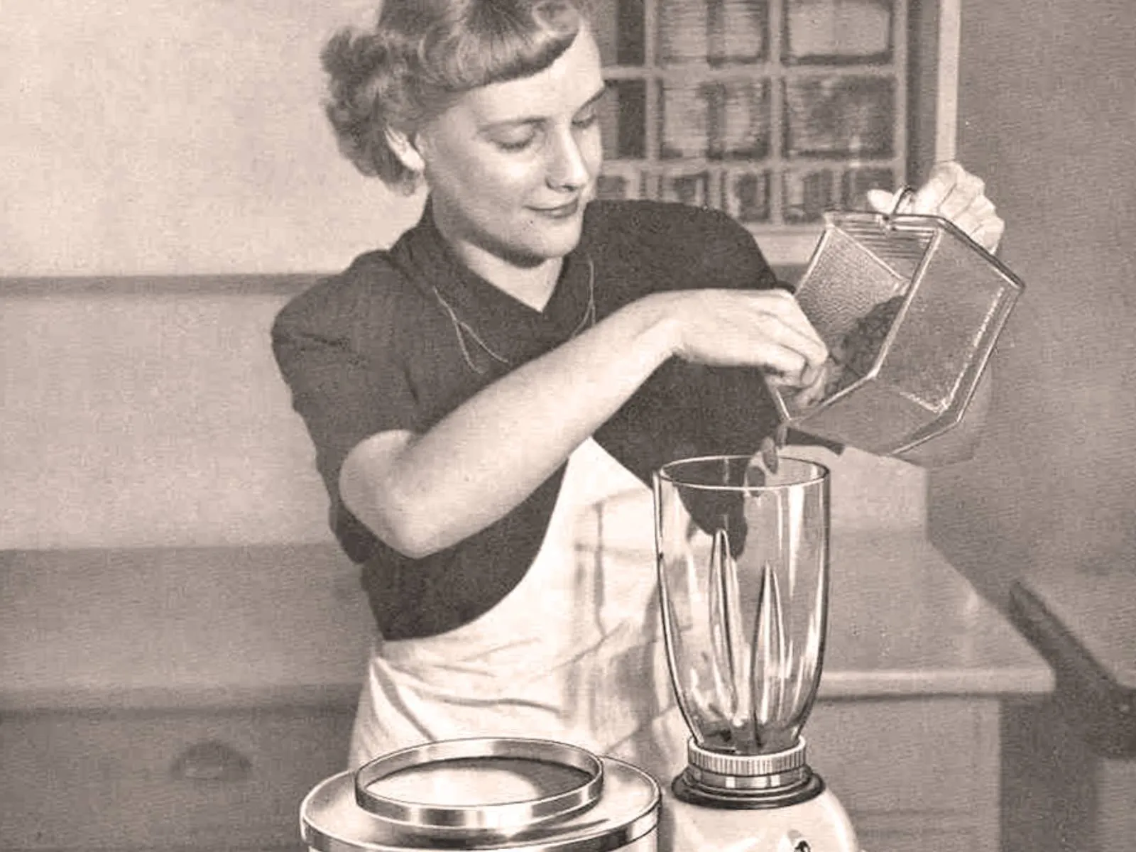 Жена користи кухињски апарат, припрема храну, винтаге црно-белу фотографију.