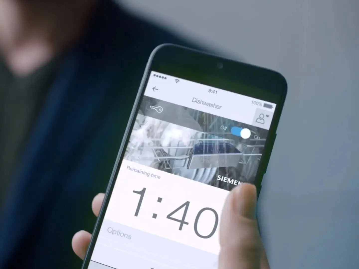 Das Bild zeigt eine Person mit einem Smartphone, das das Siemens-Logo und die Zeit 1:40 zeigt.