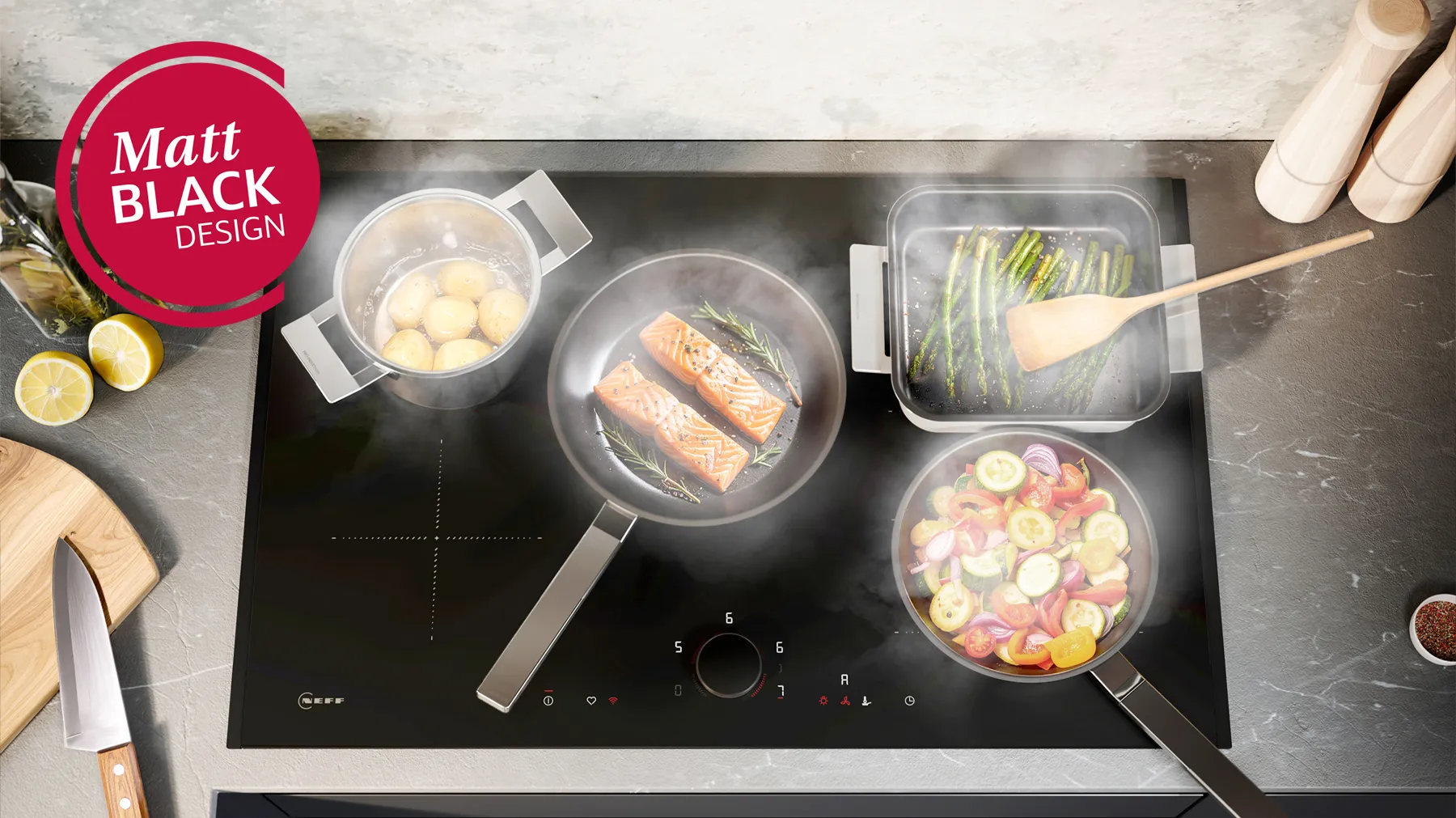 NEFF Induktionskochfeld im Matt Black Design mit Twist Pad® Bedienung, belegt mit Töpfen und Pfannen voller Gemüse, Fisch und Kartoffeln.