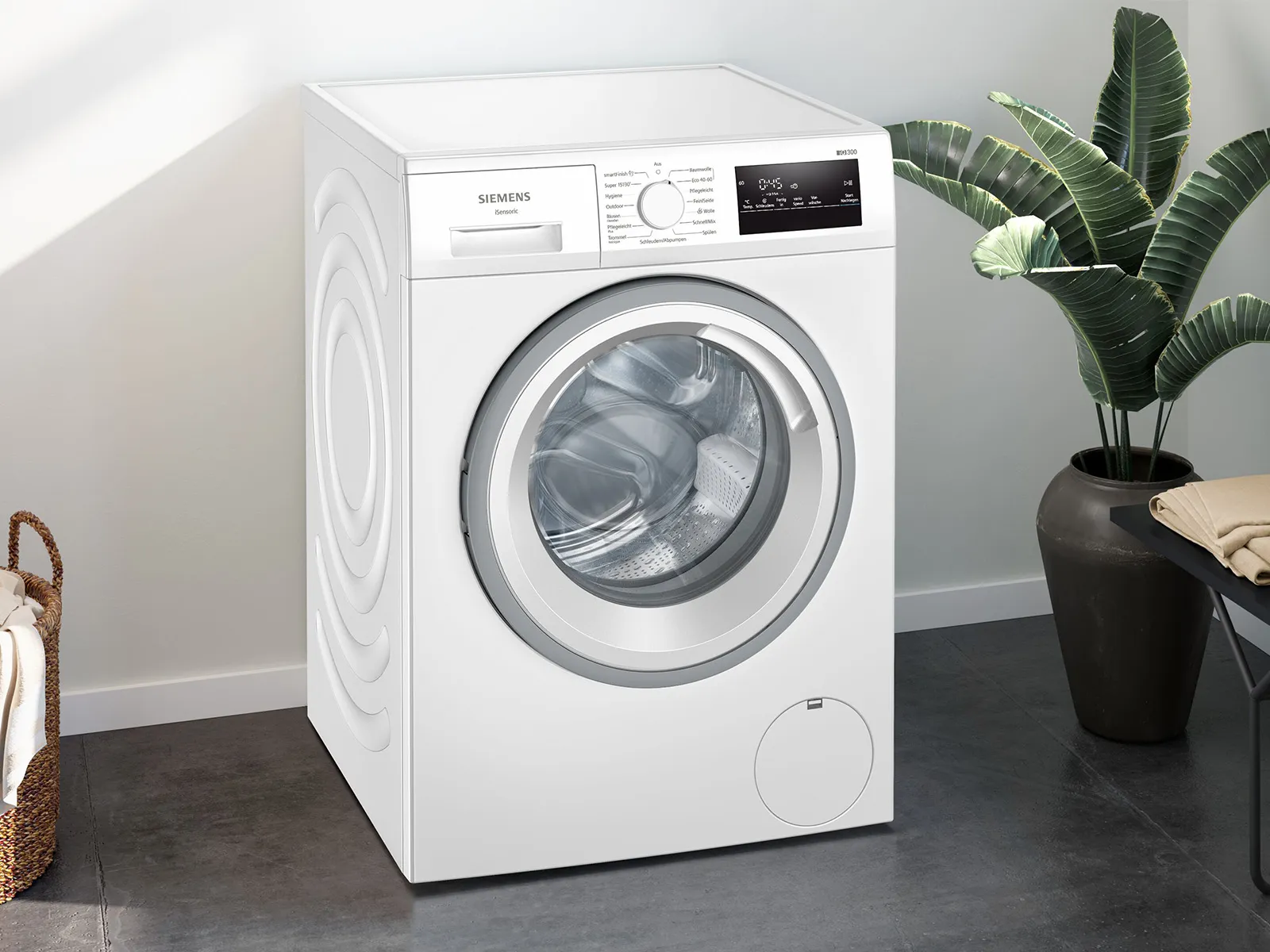 Eine elegante weiße Siemens-Waschmaschine steht an einer hellen Wand neben einer Topfpflanze und in der Nähe steht ein Wäschekorb.