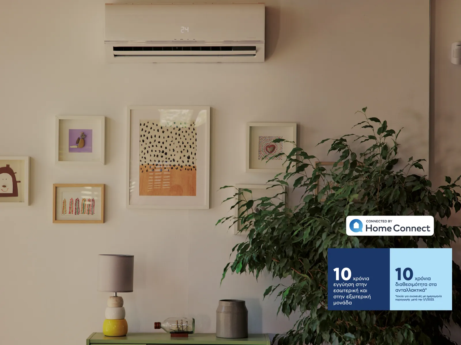 Κλιματιστικό Pitsos σε τοίχο μαζί με κάδρα κρεμασμένα από κάτω.