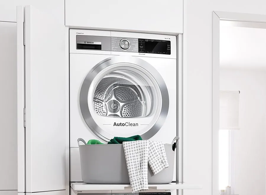 מייבש כביסה ומכונת כביסה של בוש מוצבים זה מעל זה עם מדף נשלף נוח עבור כביסה.