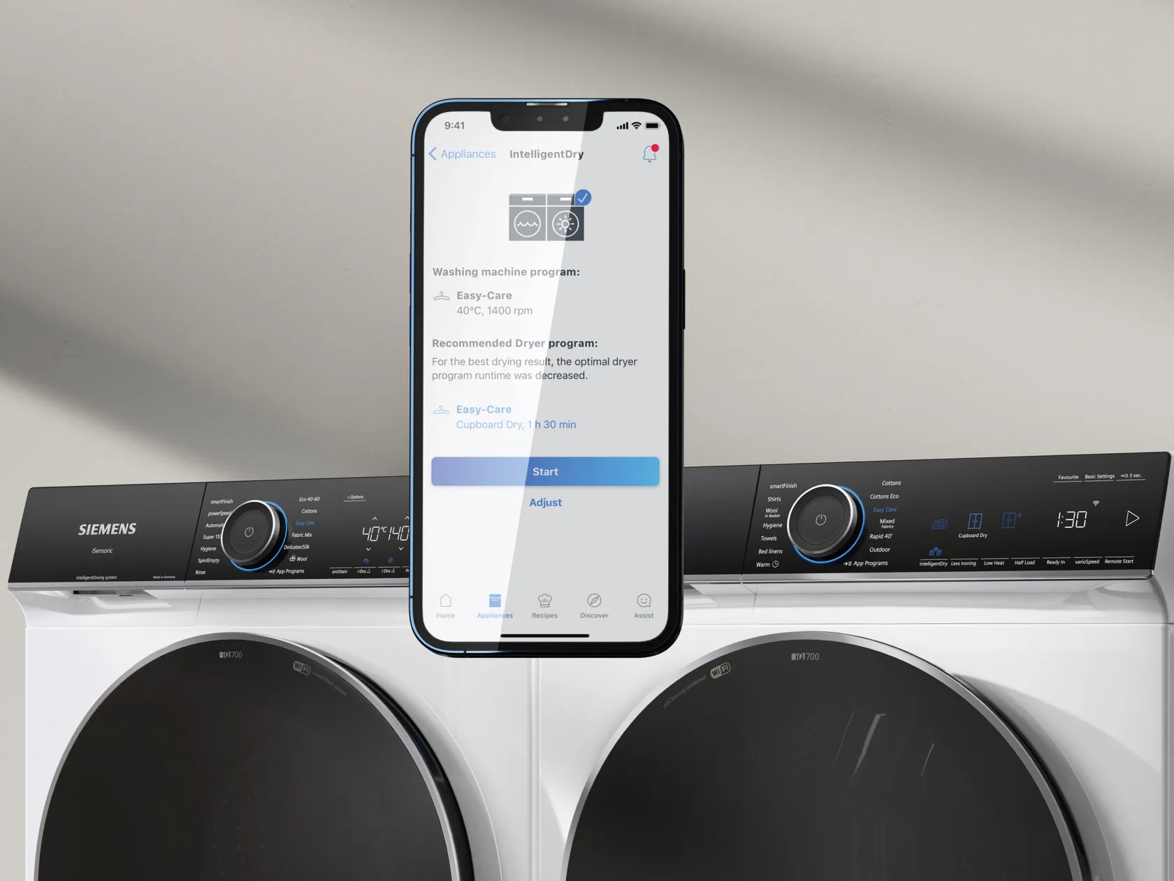 Tvättmaskin och torktumlare med mobilskärm som visas framför