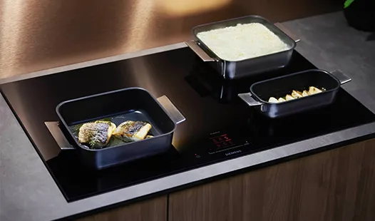 A black induction cooktop featuring two pots and pans positioned on its surface, ready for cooking.