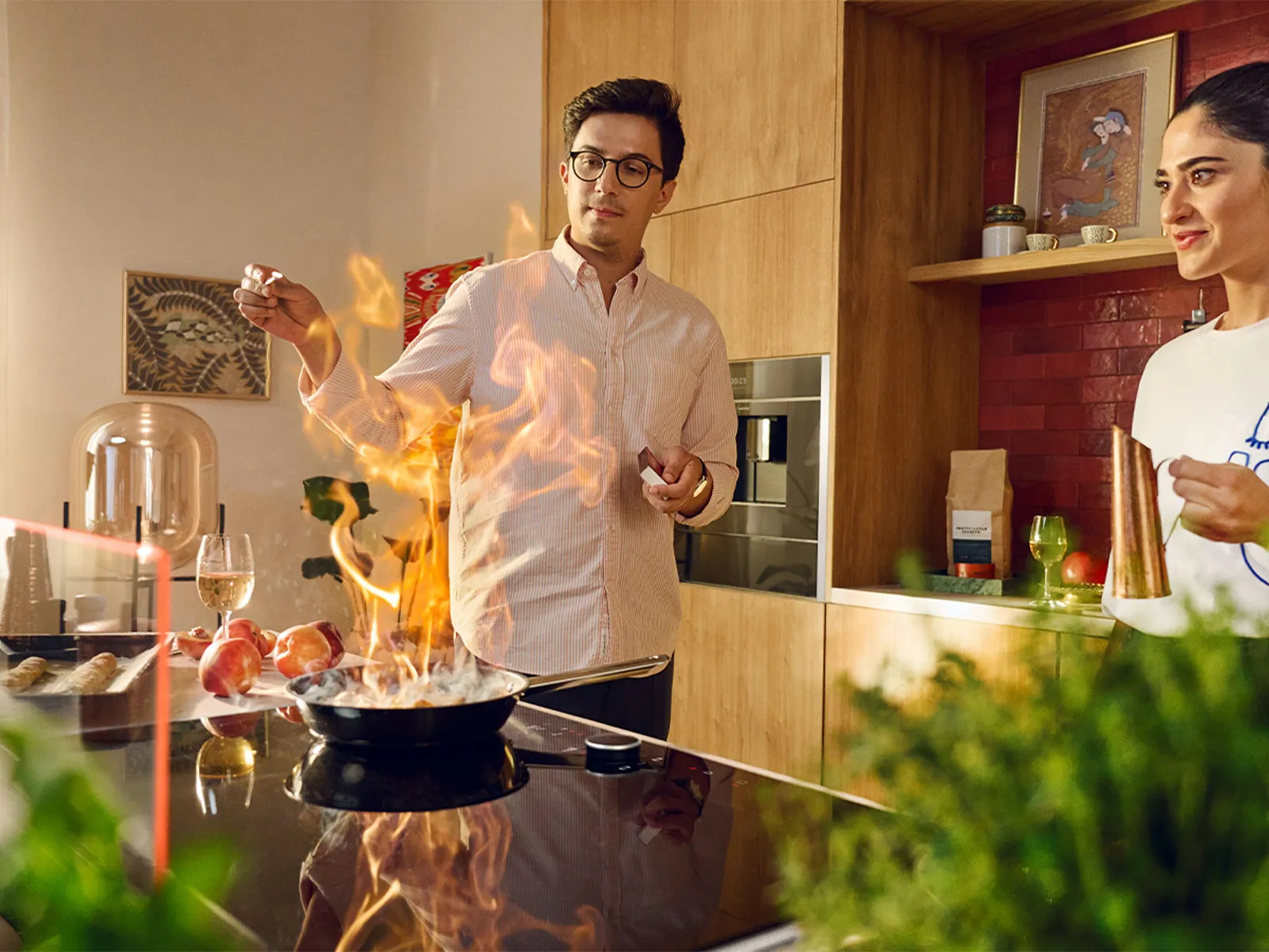 A diverse group of people cooking in a kitchen featuring a glass draft hood, engaged in meal preparation and teamwork.  