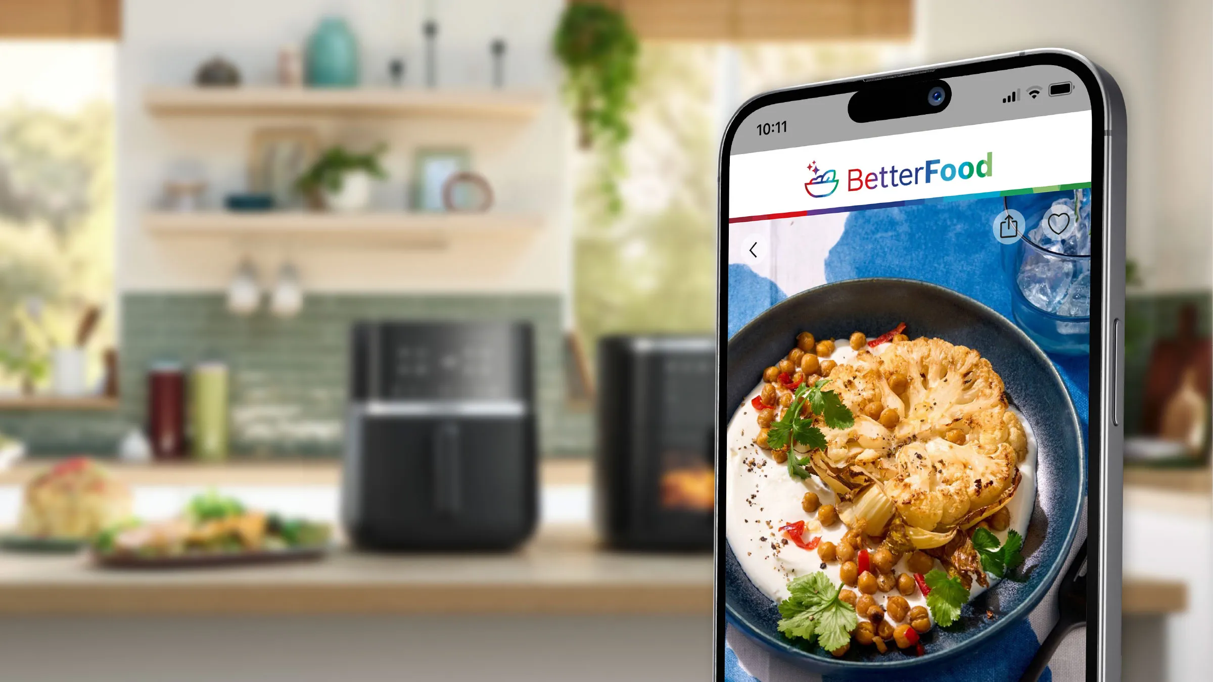 Lo schermo di un telefono cellulare mostra l'app BetterFood di Bosch. Sullo sfondo, un piano di lavoro della cucina con Air Fryer Bosch.