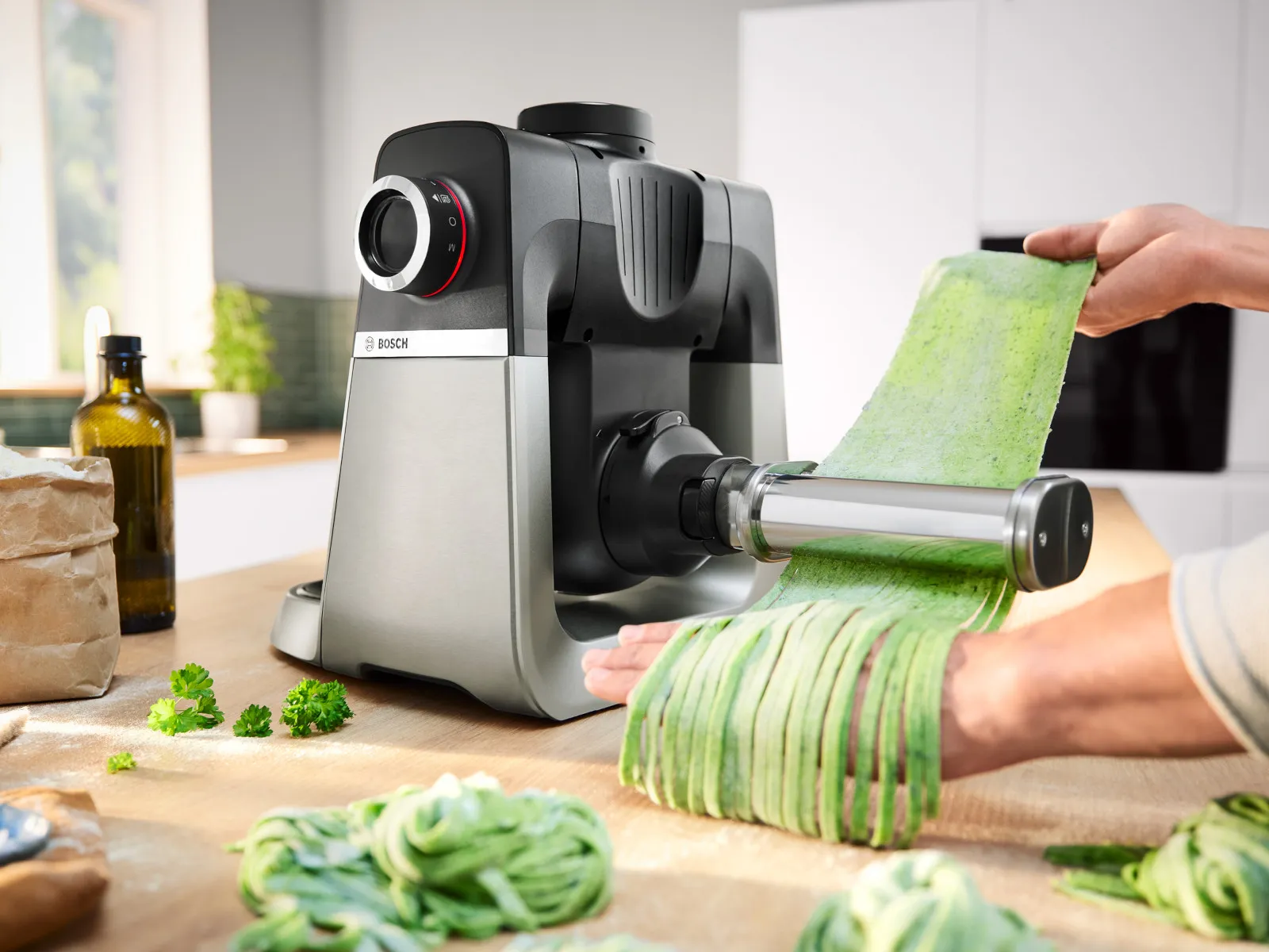 Yleiskone PastaPassion-kiinnikkeellä, jossa vihreä pasta syötetään läpi ja valmistuu tagliatelleksi.