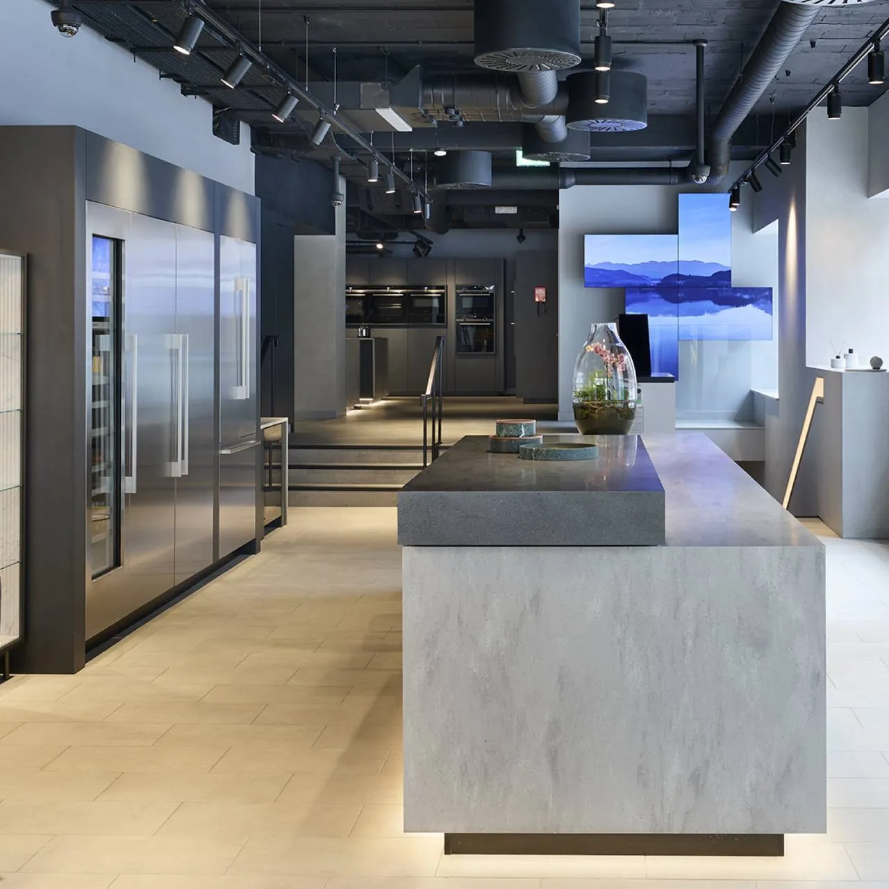 A modern kitchen in a Siemens showroom featuring a large island and a sleek refrigerator.