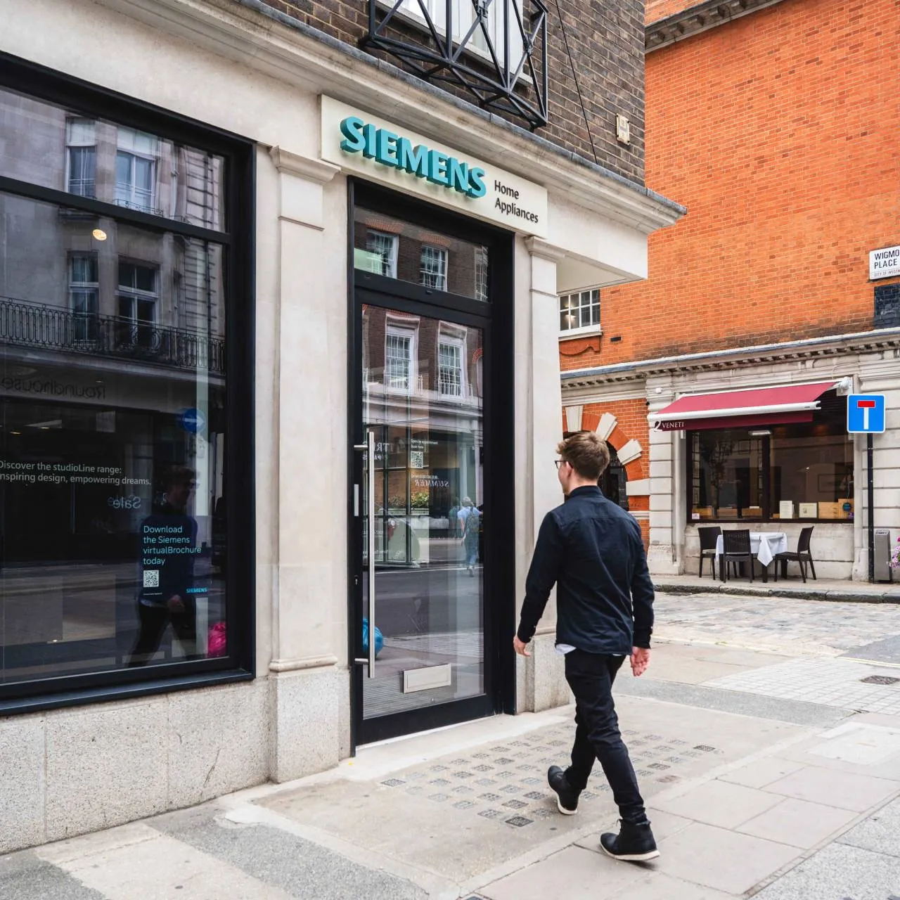 A man walks past a Siemens showroom with a prominent Samsung sign displayed in the window.