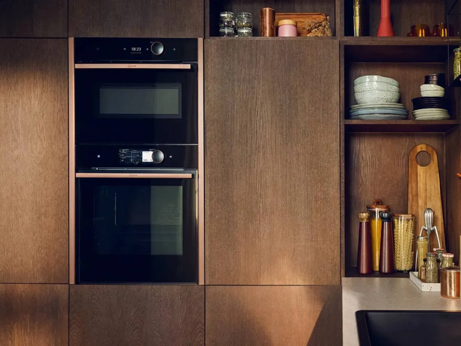 Jaukus virtuvės interjeras su medinėmis spintomis, lentynomis, prietaisais, dekoratyviniais daiktais.