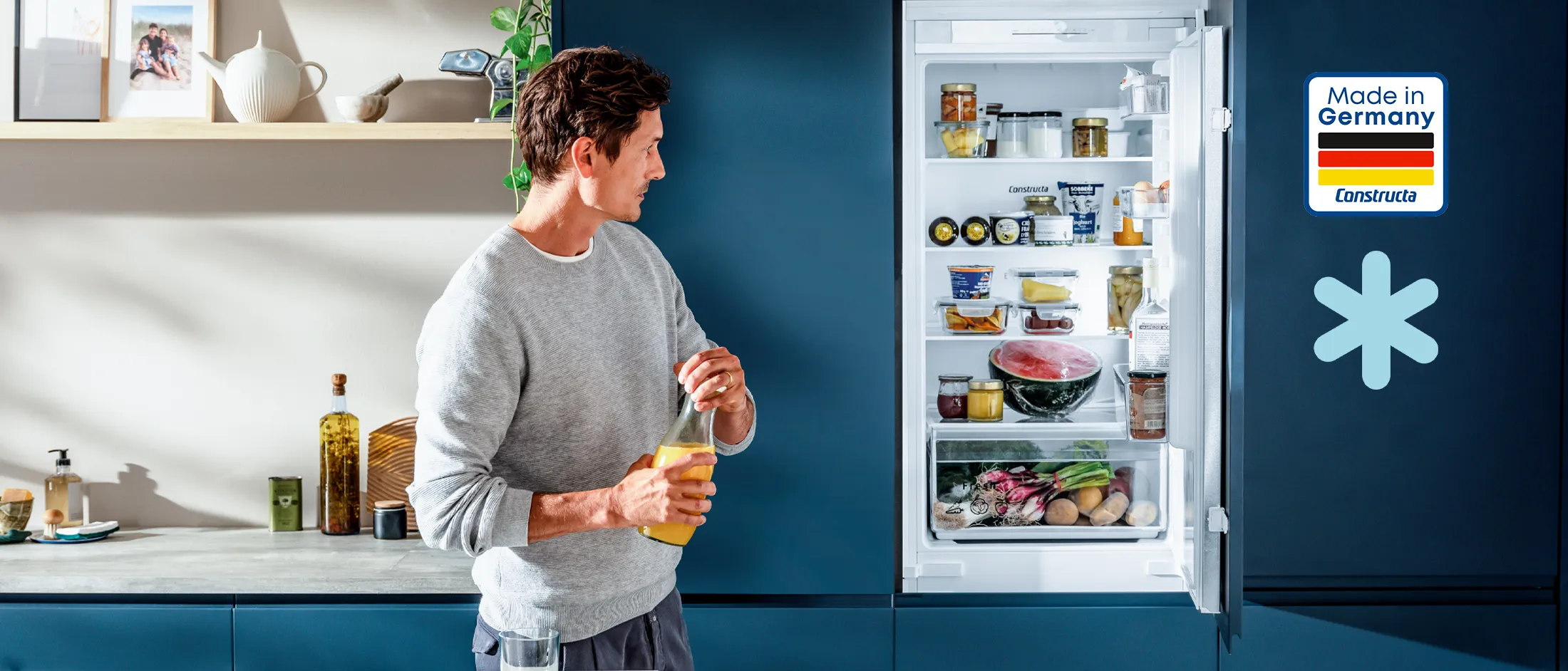 Constructa Kühlschrank Made in Germany: Eingebauter Kühlschrank mit geöffneter Tür, gefüllt mit frischen Lebensmitteln, in moderner Küche.