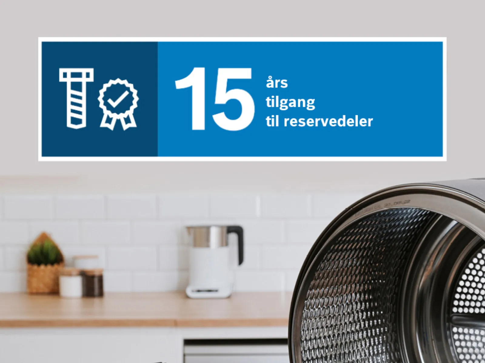 Et bilde med en trommel til en vaskemaskin, reservedeler og et skilt med teksten «15 års tilgang til reservedeler» på norsk.