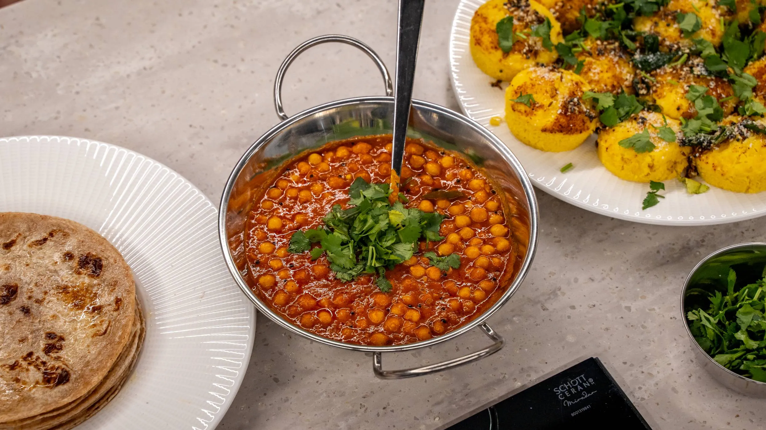 A table set with Indian dishes and a smartphone, showcasing a vibrant array of traditional food.