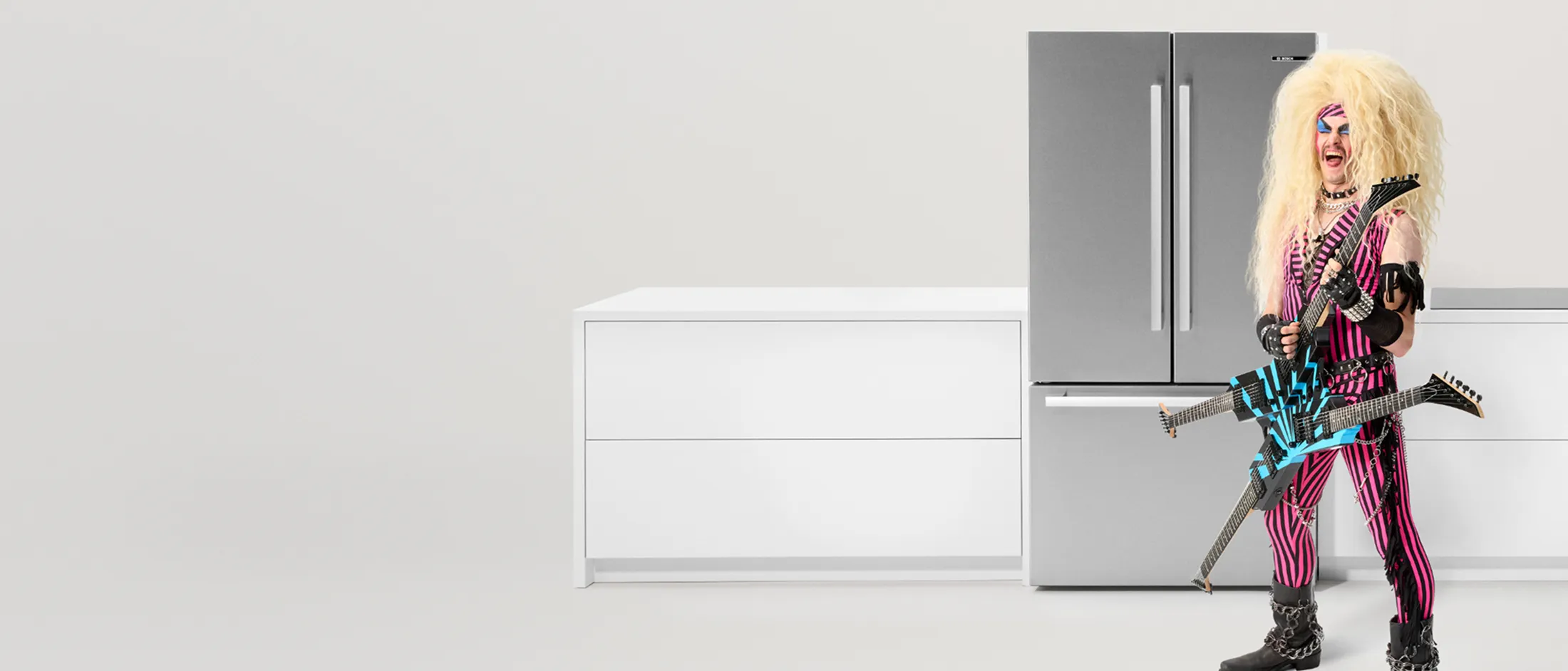 A spacious kitchen showcases a modern refrigerator filled with organized food and drinks, surrounded by plants.