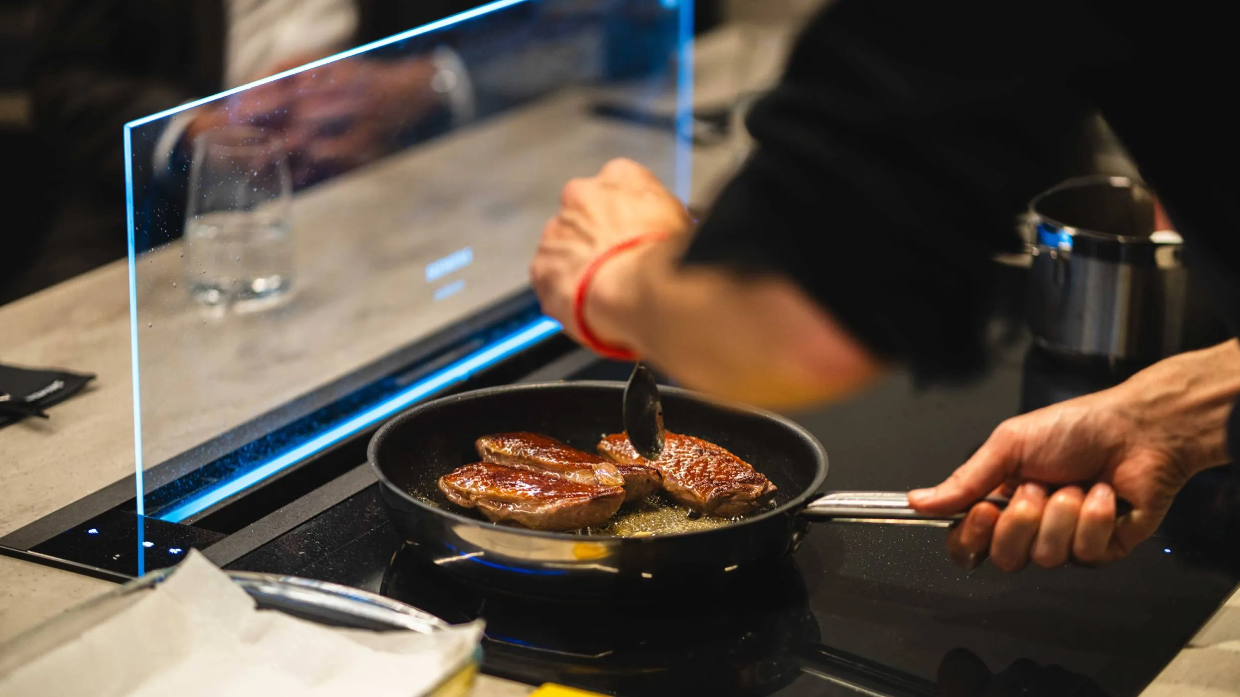 A person cooking a steak on a stovetop, focused on achieving the perfect sear and doneness.