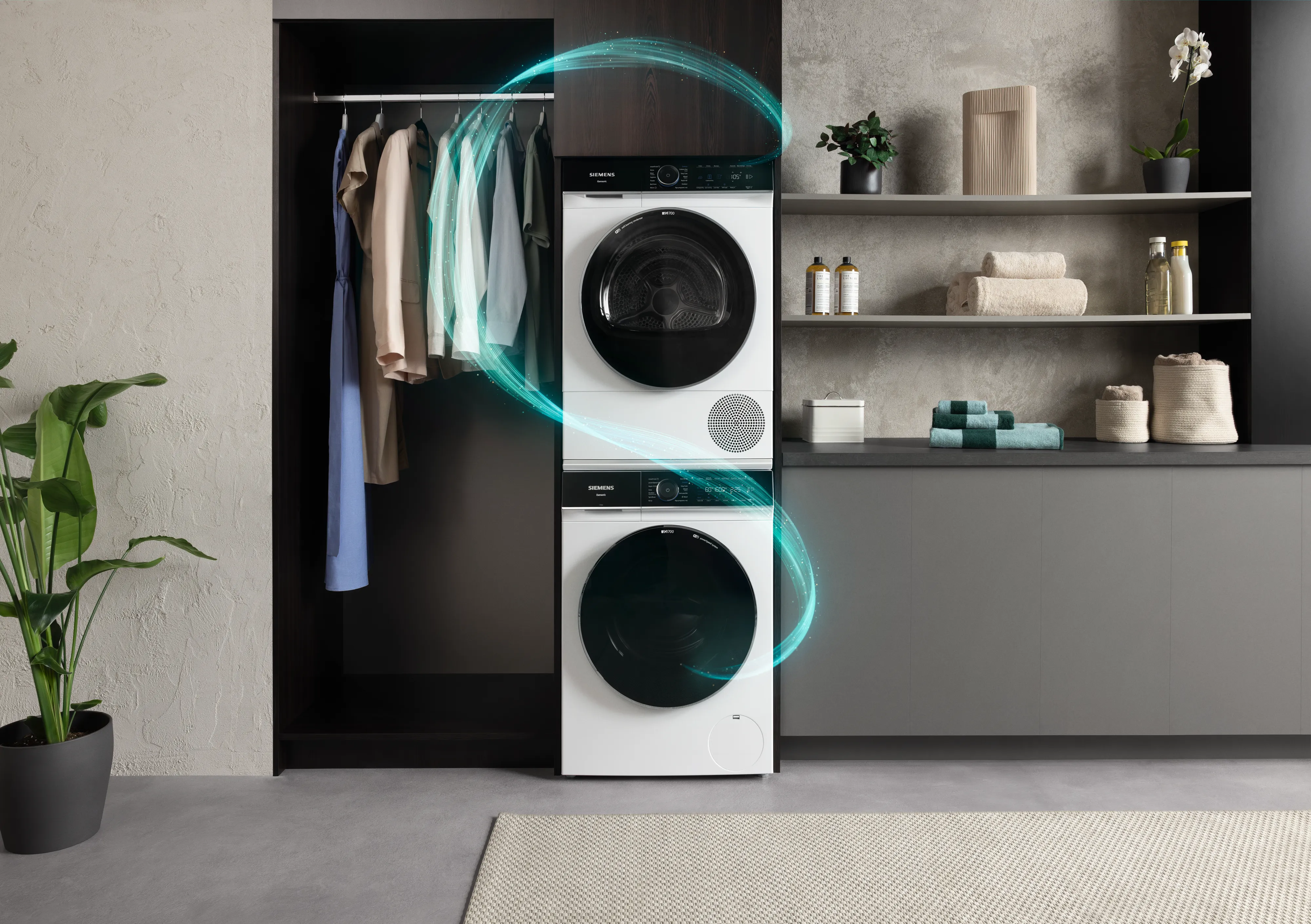 Moderne wasruimte met bekroonde wasmachine en droger, planken met handdoeken en hangende kleding.