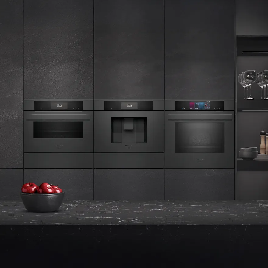 Modern kitchen with built-in black appliances, including oven, coffee machine, and microwave, set against dark cabinetry and countertop.