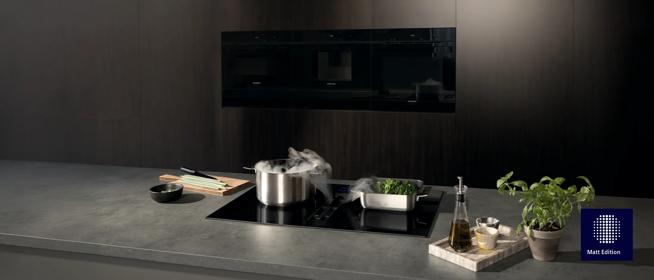 Moderna cucina Siemens con pentola fumante su piano cottura a induzione, verdure fresche e ingredienti per cucinare sul bancone.