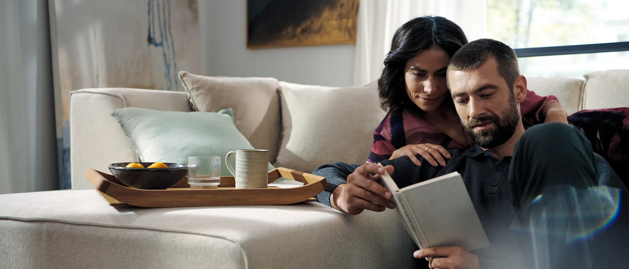 Mann und Frau sitzen gemeinsam auf einem Sofa und schauen auf ein Tablet