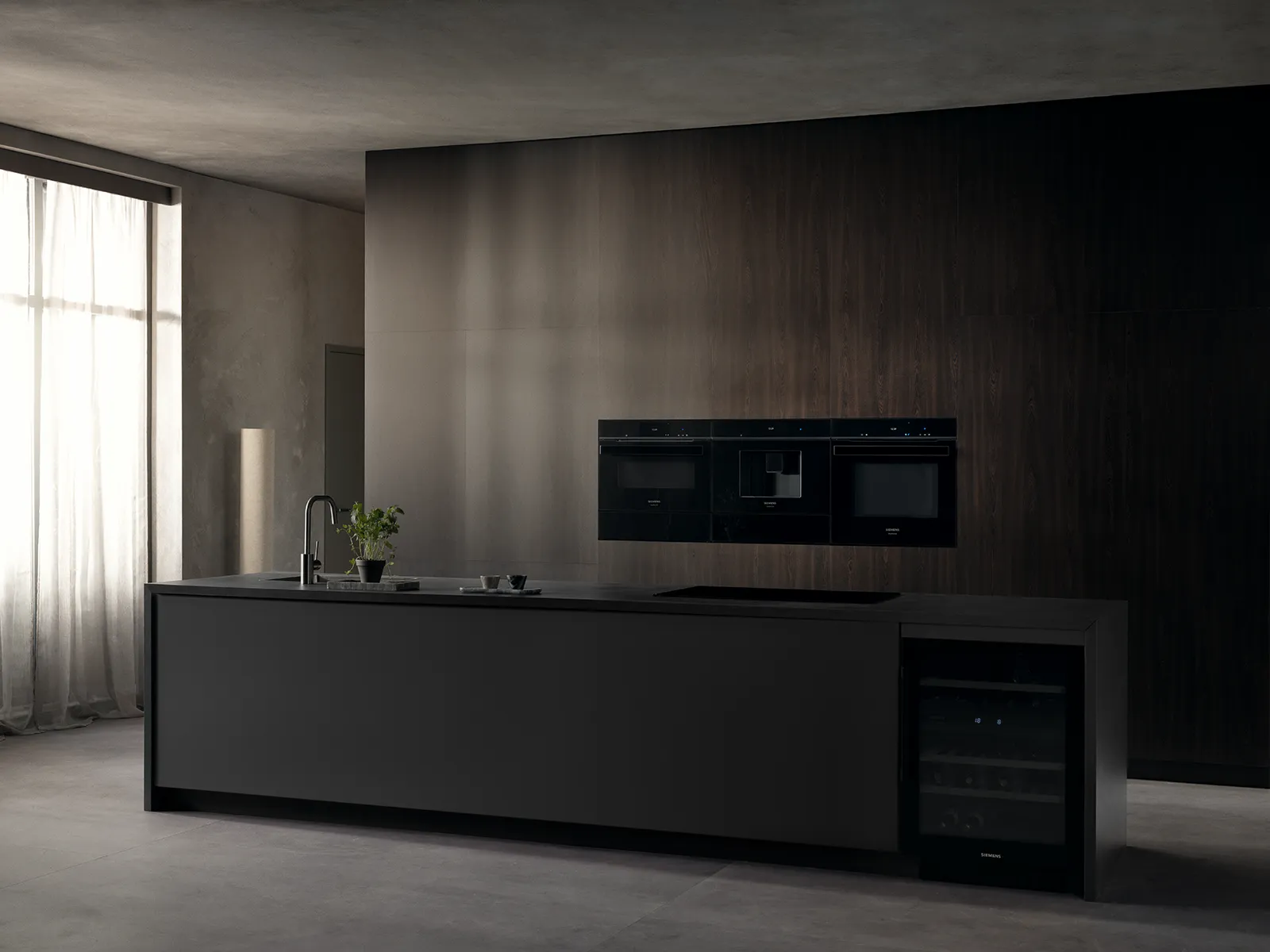 Elegancka, nowoczesna kuchnia z ciemną wyspą, wbudowanymi urządzeniami i dużymi oknami z lekkimi zasłonami przepuszczającymi naturalne światło.
