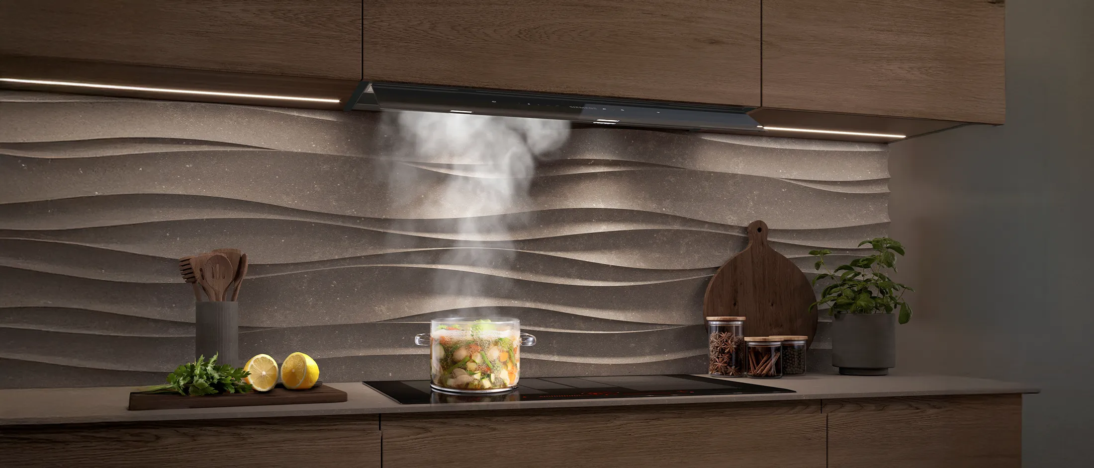 Cuisine moderne avec des armoires en bois, un dosseret texturé, et une casserole en train de cuire à la vapeur sur la cuisinière sous une hotte.