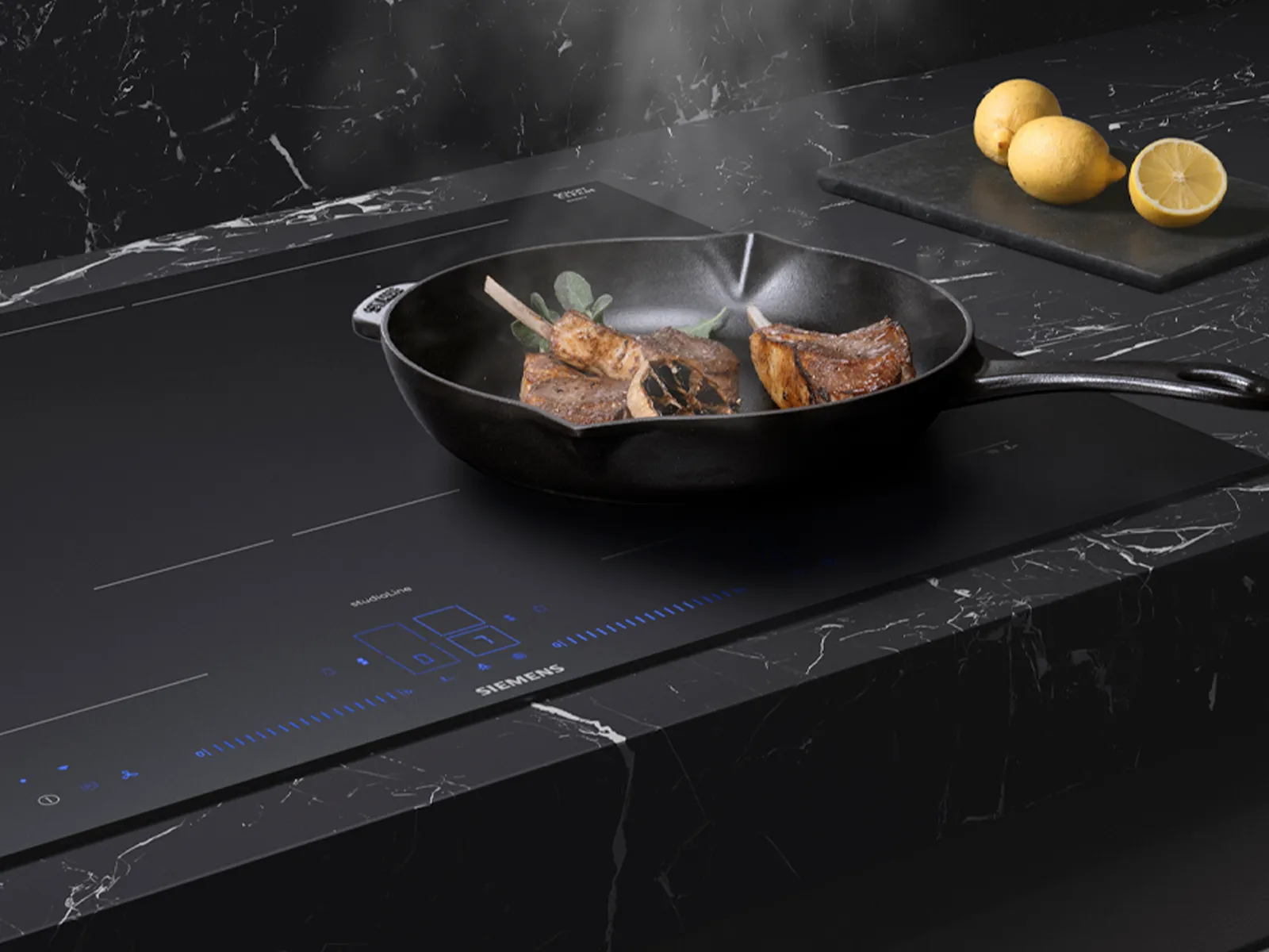 Kød, der syder på en sort induktionskogeplade, kombineret med friske citroner og en stilfuld marmorbordplade.