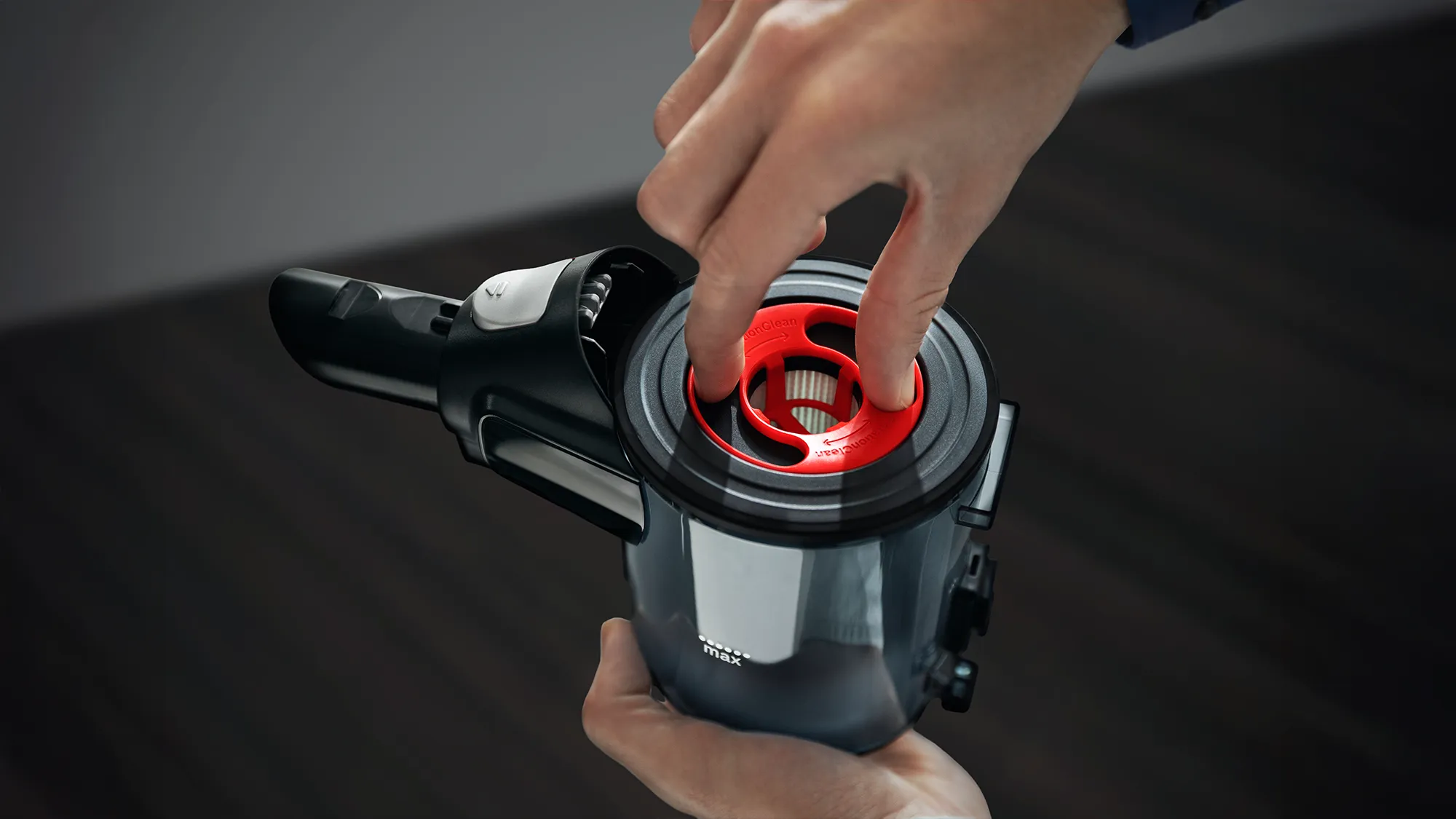 A person removing the red filter from a vacuum cleaner's dustbin.