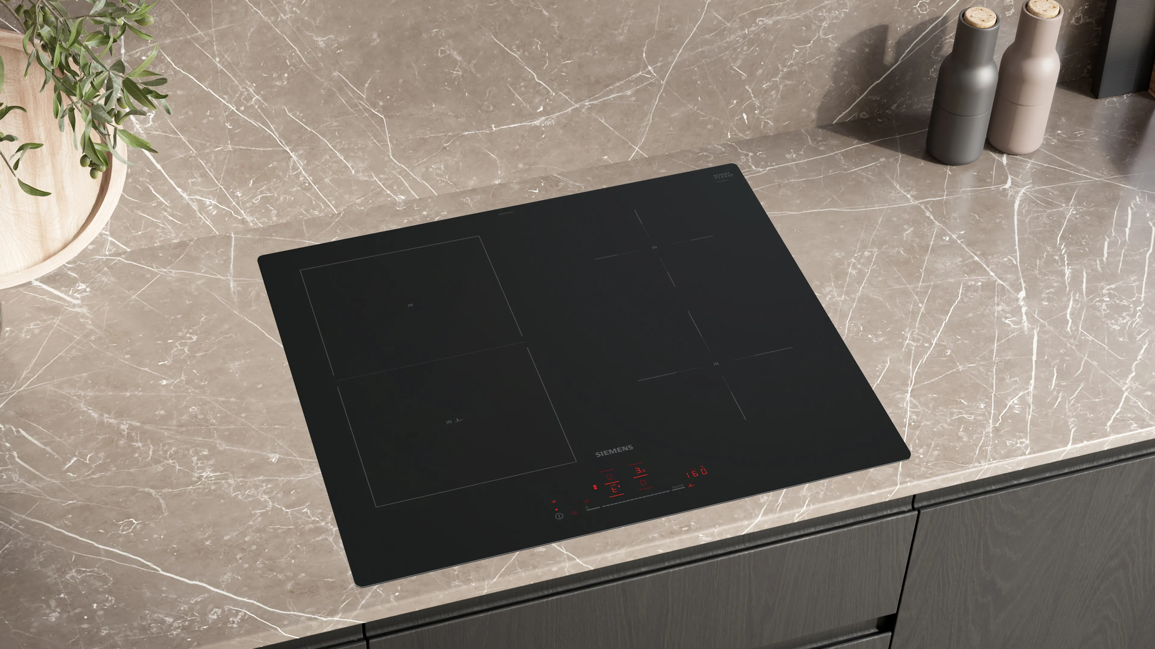 Elegancka czarna kuchnia o nowoczesnym designie: płyta grzewcza z parującą patelnią, na blacie misa czerwonych jabłek i soczysta cytryna.