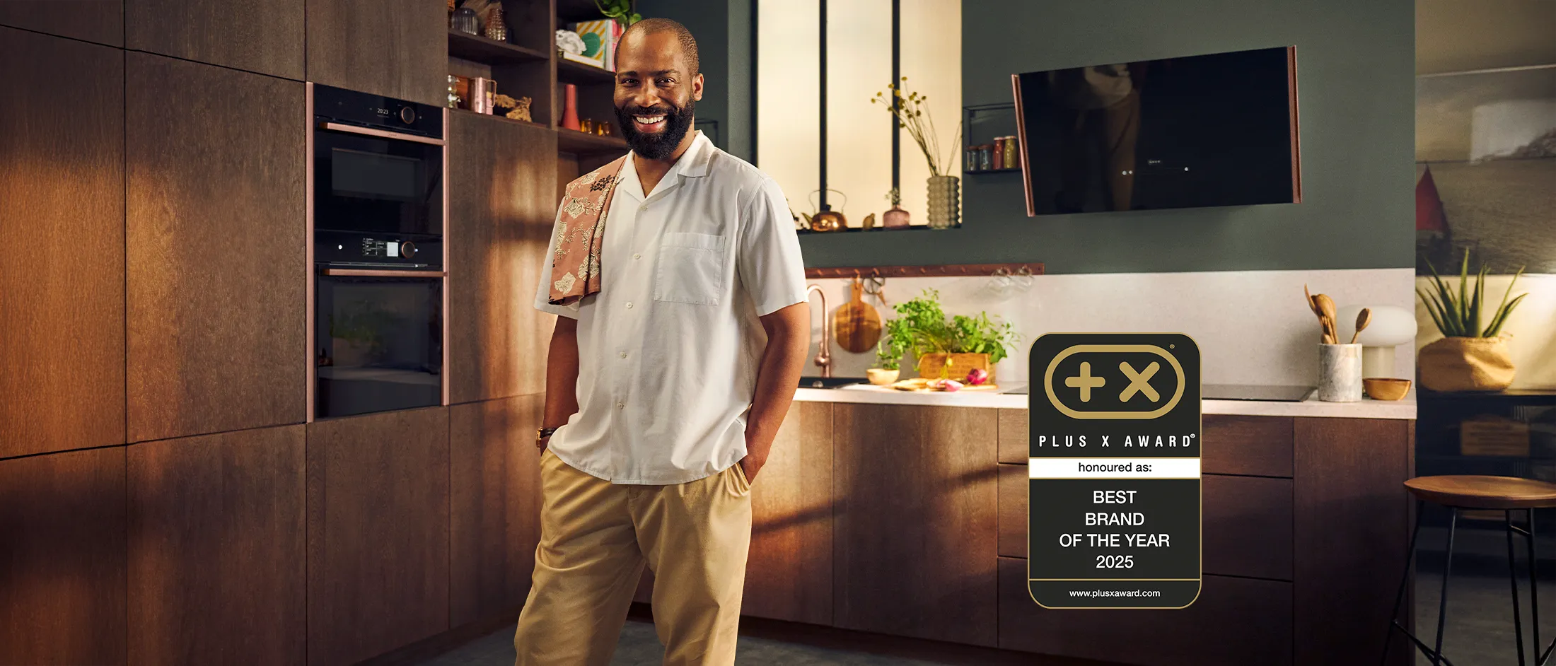 Smiling man in a modern kitchen with Neff appliances, exuding style and warmth in a welcoming atmosphere.