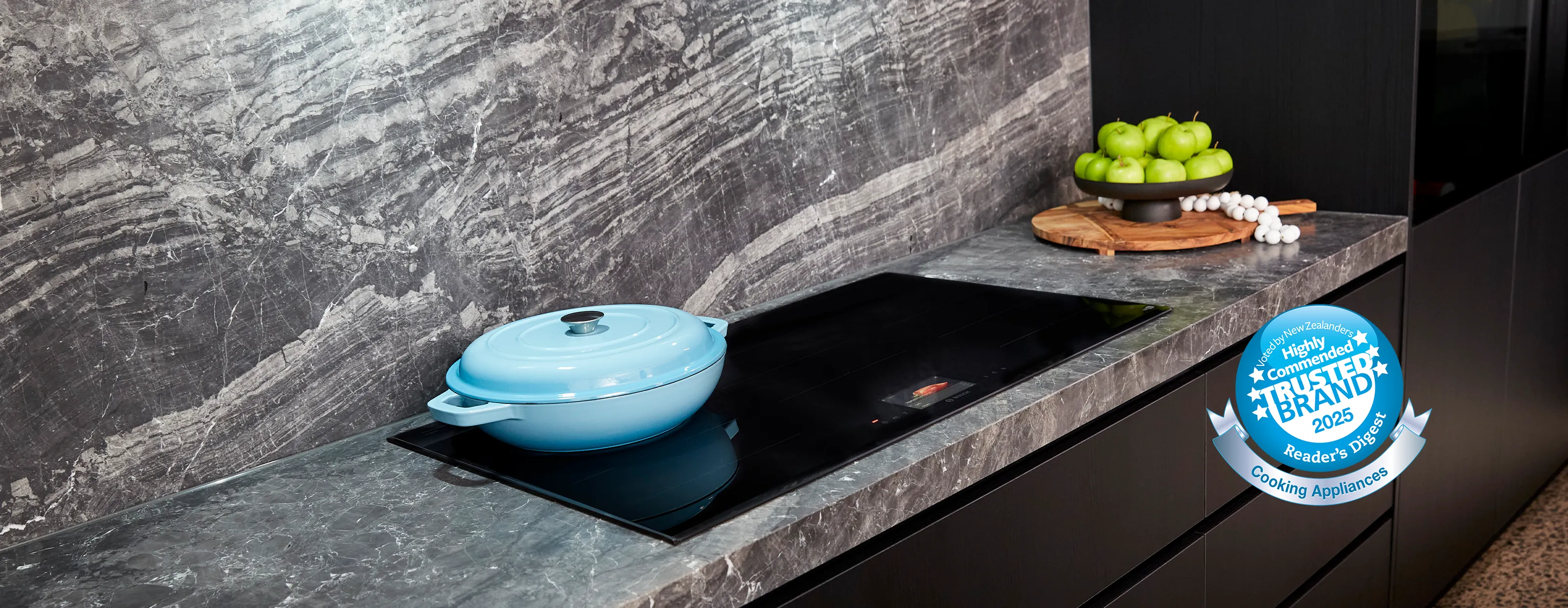 Modern kitchen with a Bosch built-in oven, minimalist wooden cabinetry, and wide induction hob on the island.
