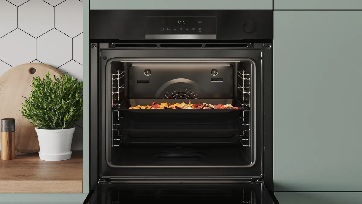 Geöffneter Bosch Einbau-Backofen mit Air Fry Funktion, Air Fry Blech mit knusprig zubereiteten Speisen im Garraum sichtbar.