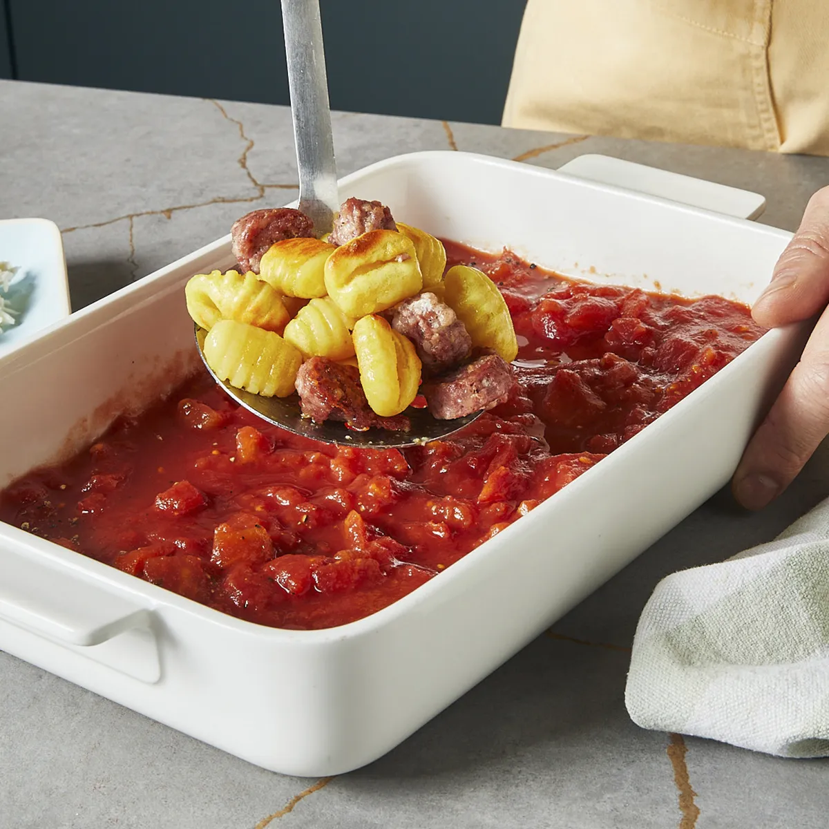 Gebackene Gnocchi und Bratwurst in die Auflaufform mit der Tomatensauce legen.