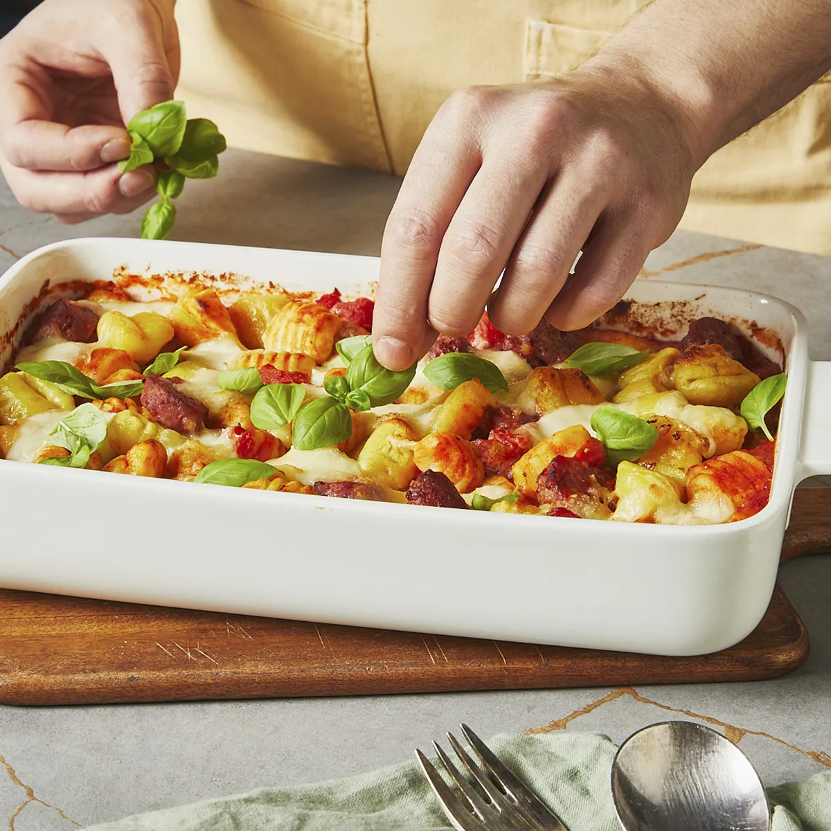 Einzelne Basilikumblätter werden auf die gebackenen Gnocchi gelegt.