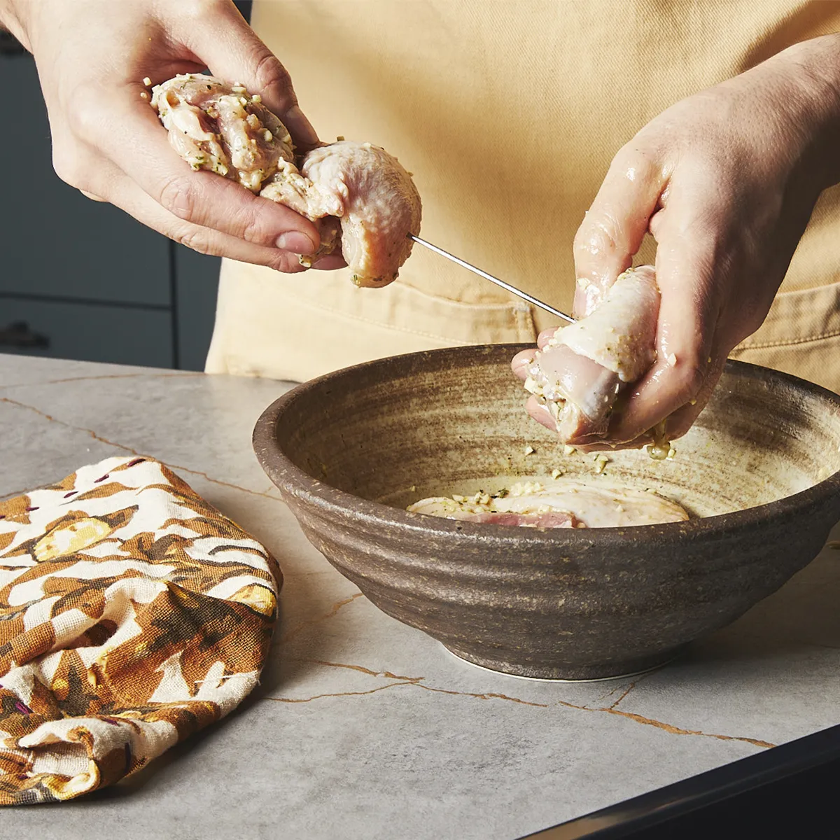 Putting marinated chicken breasts on a skewer