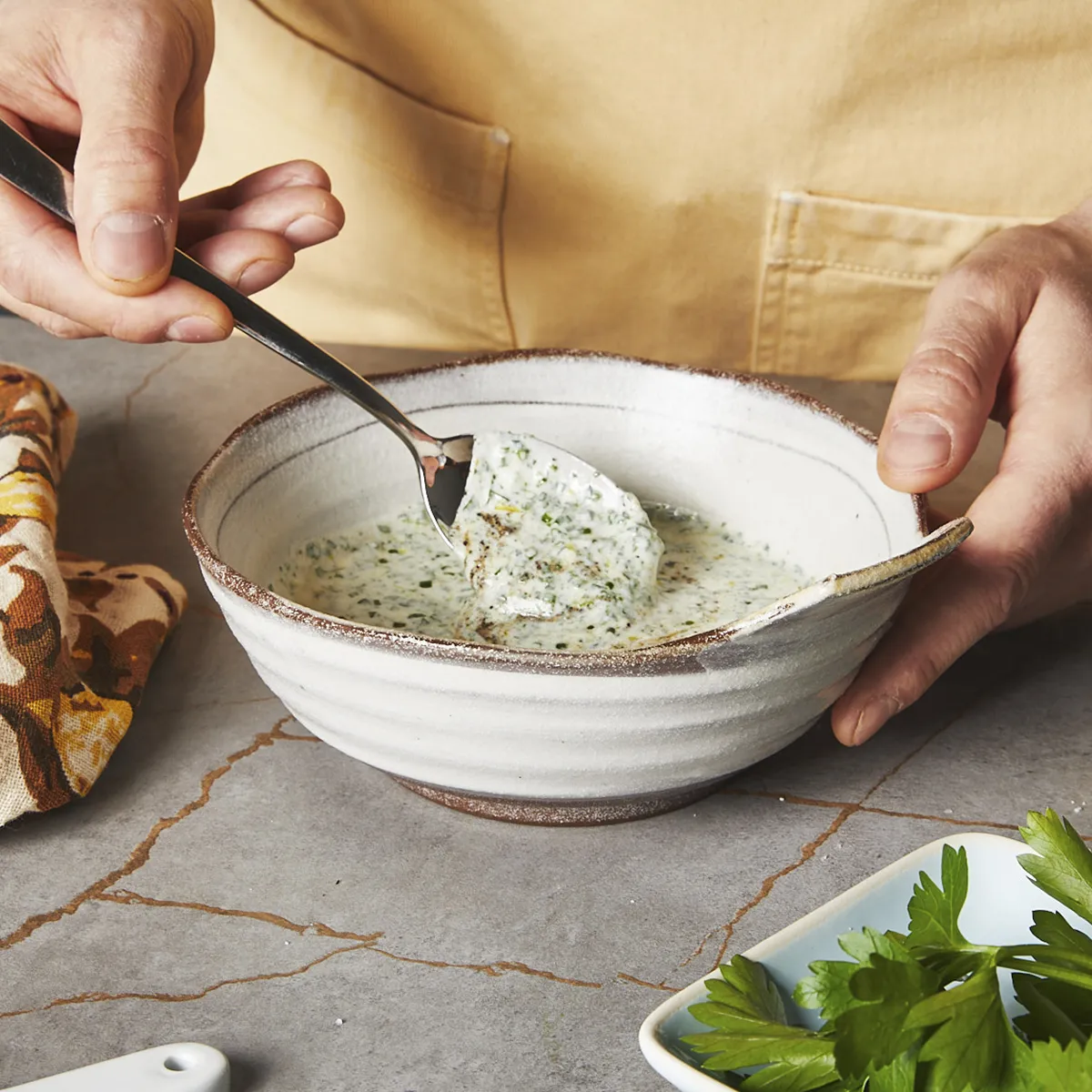 Mixing herbs into yogurt dip with a spoon
