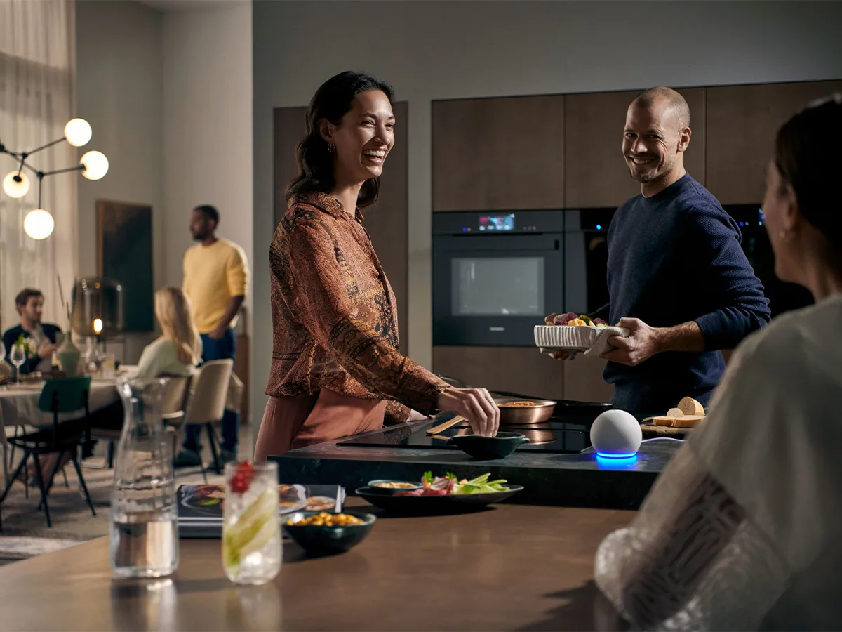 Friends cooking around hob in kitchen