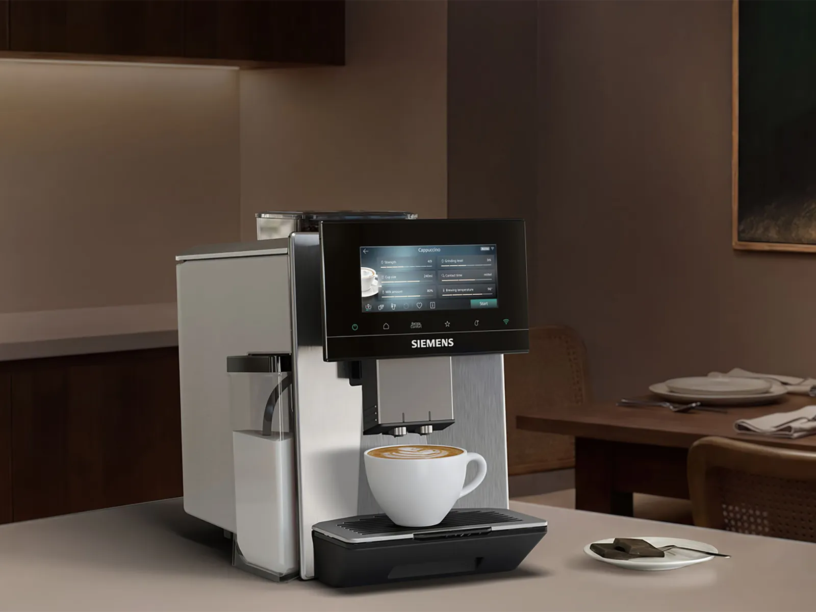 Siemens coffee machine with touchscreen and ready cappuccino in white cup: warm, softly lit kitchen in the background with dark cabinets, a small plant, and a set dining table with wine and candlelight.