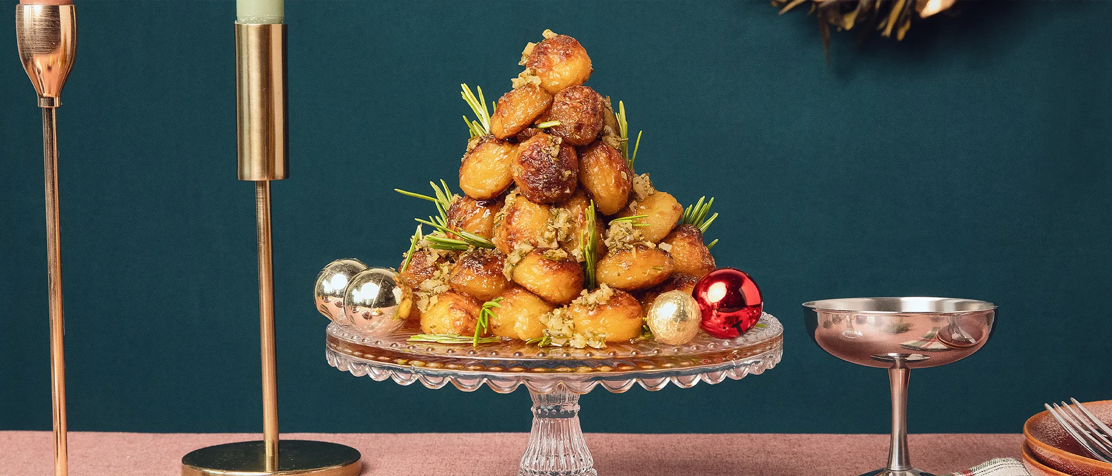 Goldbraune, knusprige Röstkartoffeln, angerichtet in Kegelform auf einem Tortenständer, in einem modernen Weihnachtsambiente.