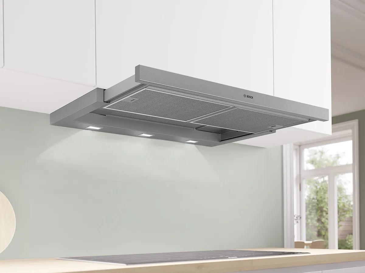 View of white kitchen with a silver integrated slide-out rangehood.