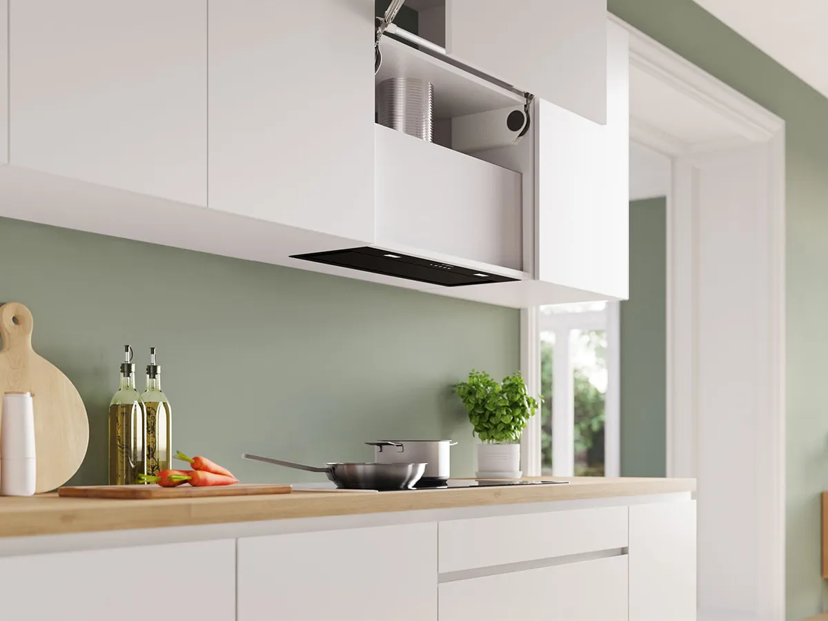 View of kitchen with green walls and white benchtops, featuring a black cooktop and rangehood.