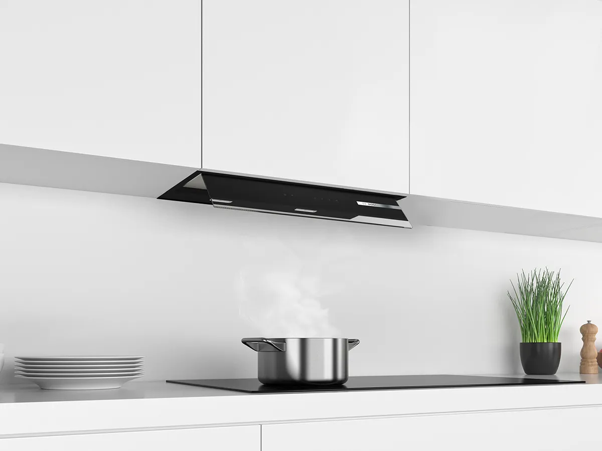 Black integrated rangehood atop a pot steaming.