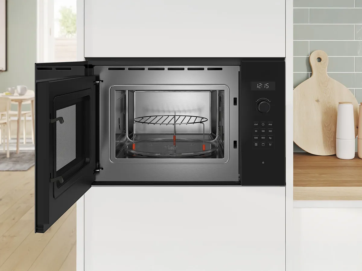 Built-in microwave with door open and integrated into a light green kitchen.