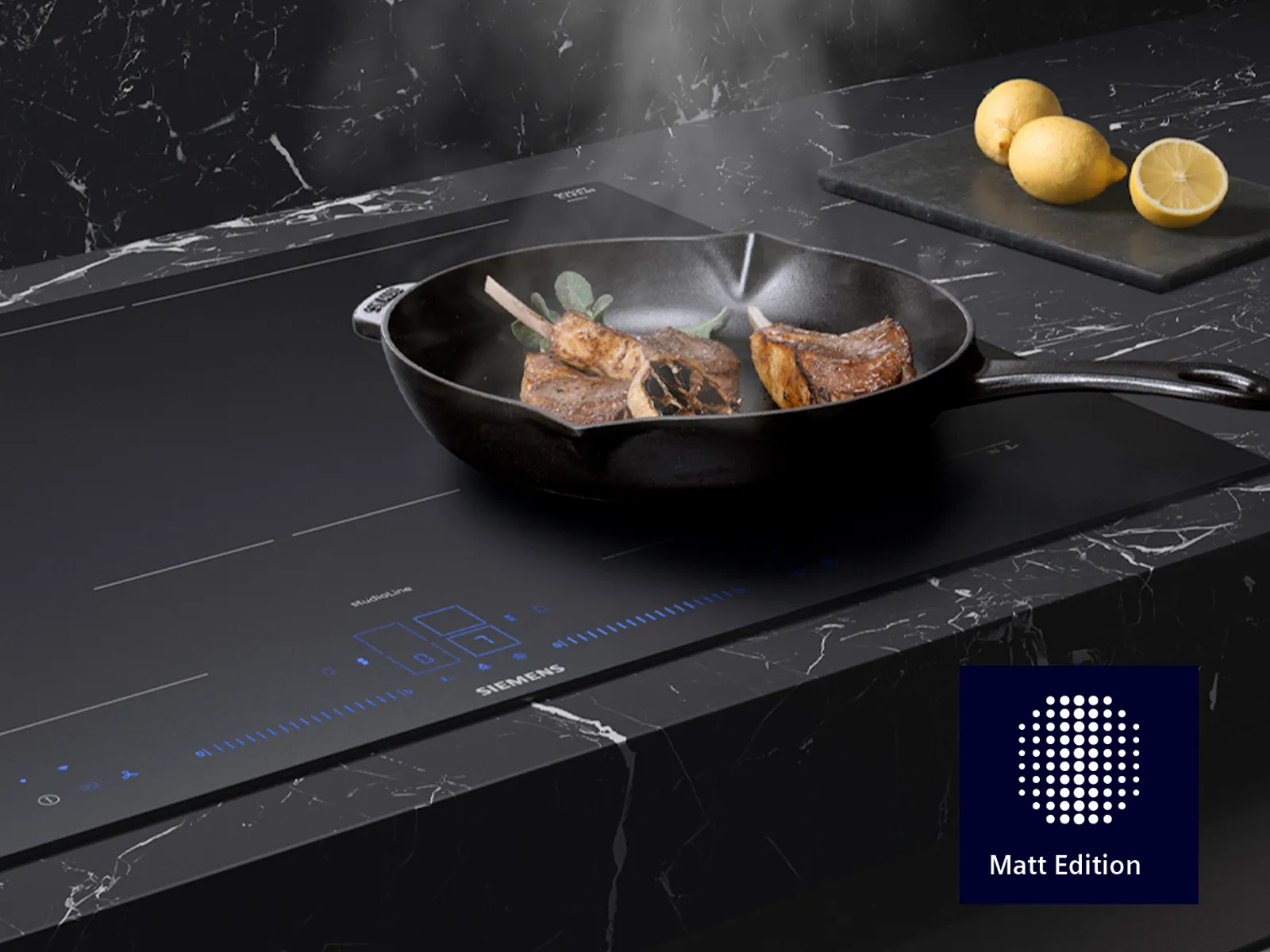Zischendes Fleisch auf einem schwarzen Induktionskochfeld, kombiniert mit frischen Zitronen und einer eleganten Marmorarbeitsplatte.
