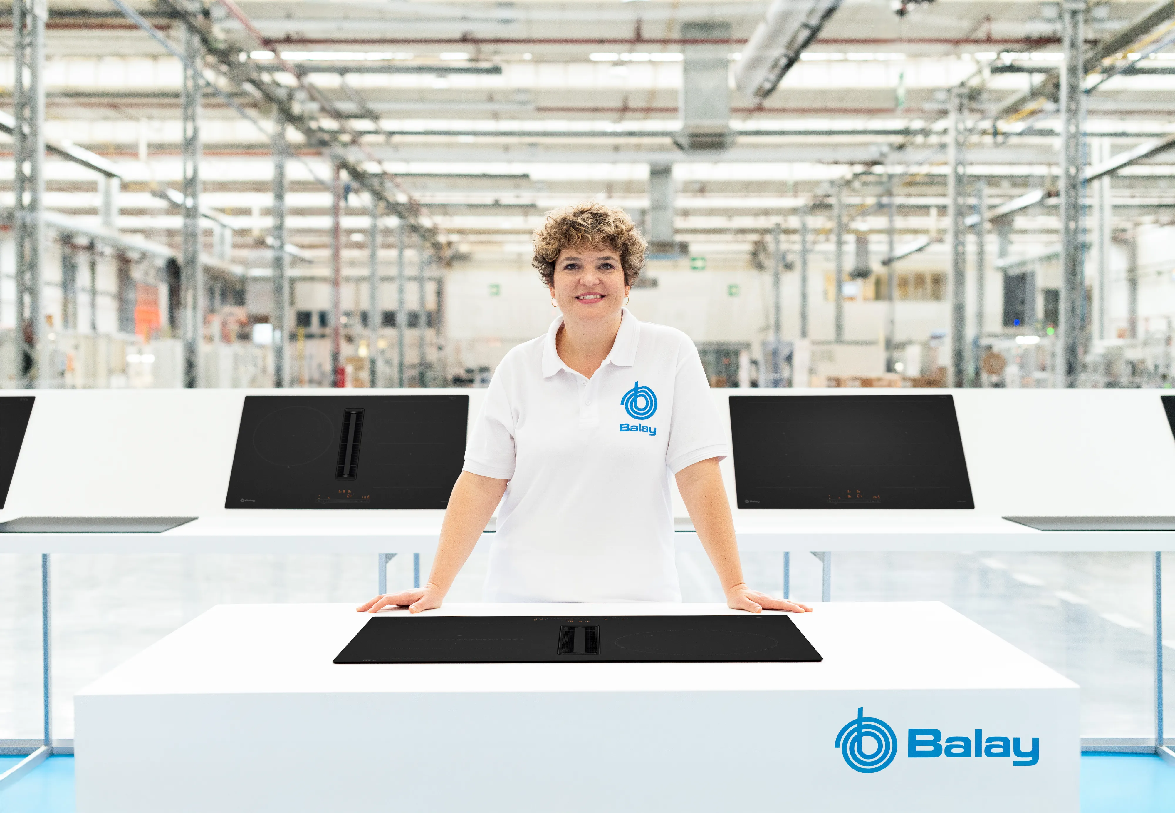 Empleada con uniforme de Balay situada enfrente de una placa mate