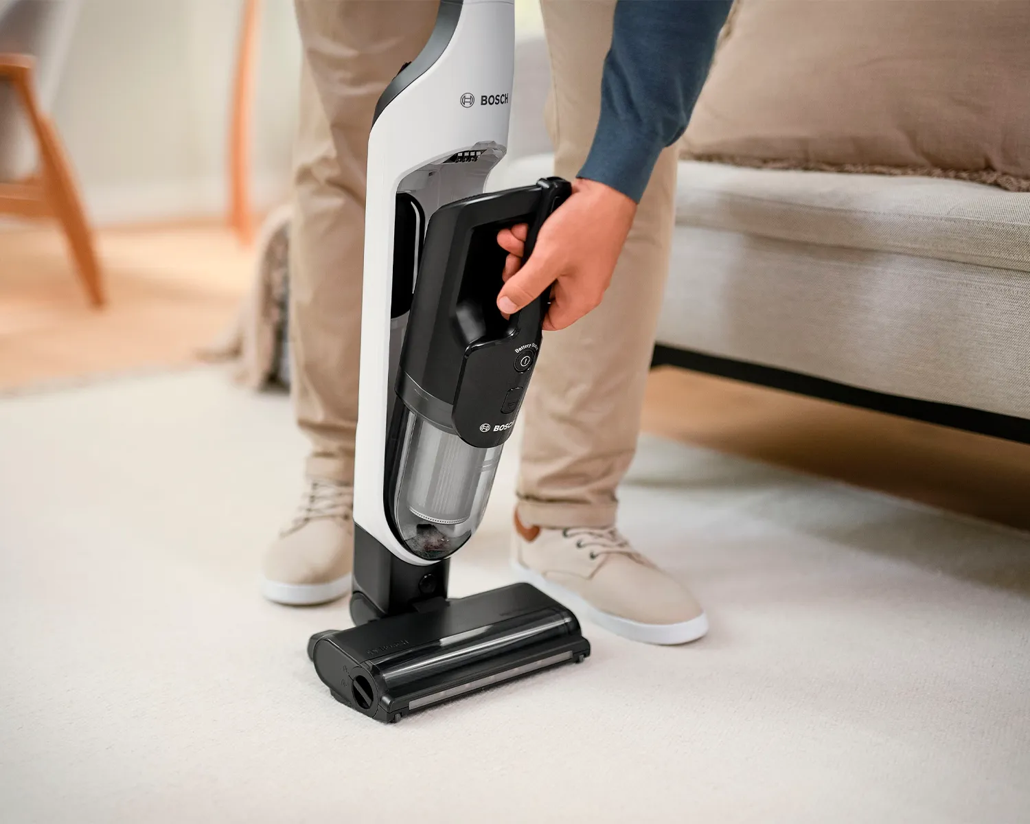 Person using a Bosch cordless vacuum cleaner on a hardwood floor.